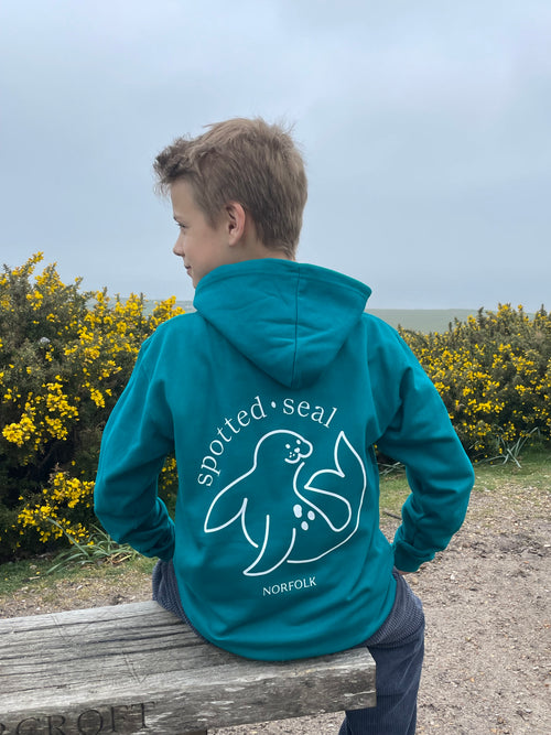 model showing back of children's spotted-seal hoodie in teal