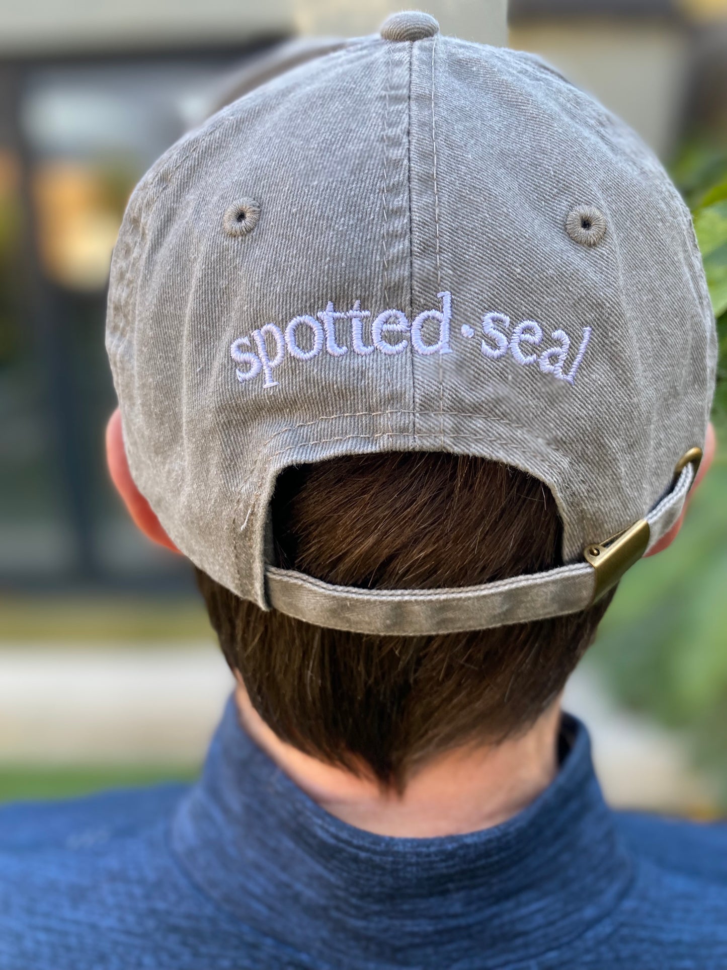 model showing back of spotted-seal cap in grey Shingle colour and embroidered spotted-seal