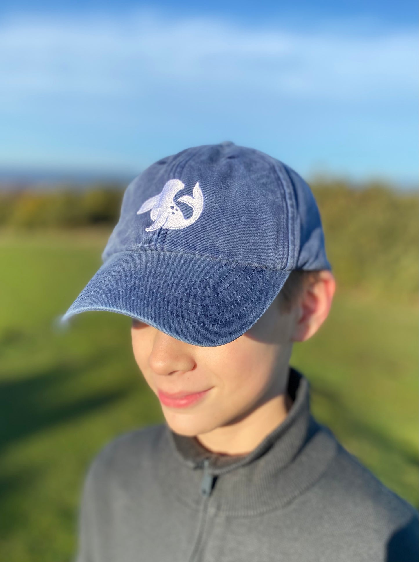 front of spotted-seal cap in navy modelled with embroidered seal