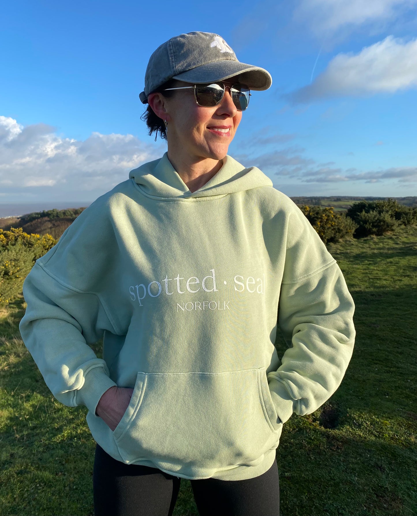 Model on Norfolk coast in spotted-seal women's slouch hoodie in Sea foam pistachio green