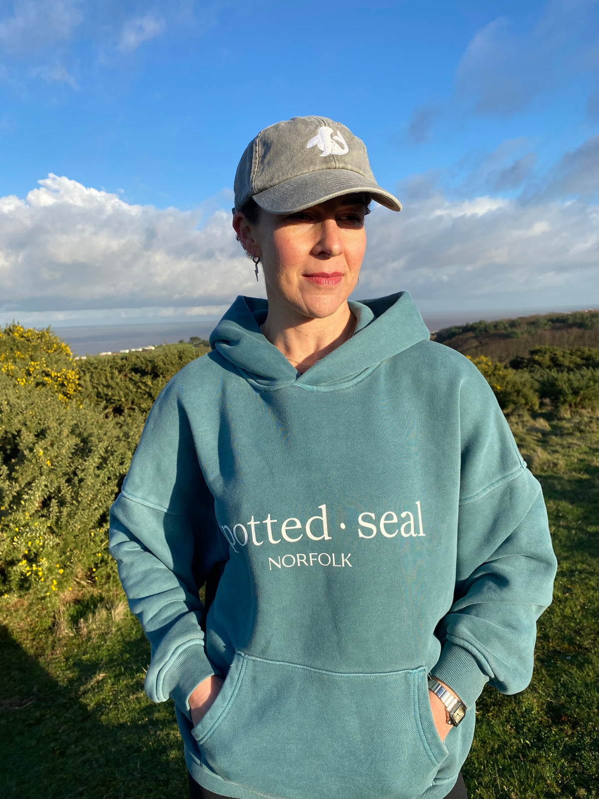 model on Norfolk coast in spotted-seal women's slouch hoodie in ocean depth green